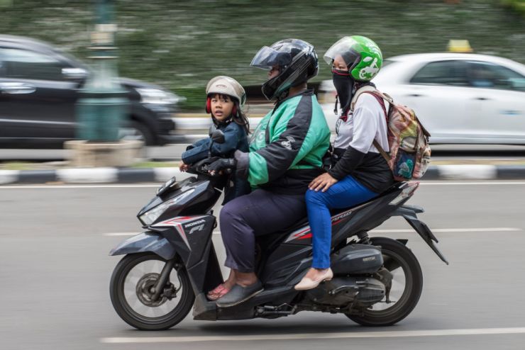 Go-jek buys coins. Ph in philippines power move Three people sitting on a scooter